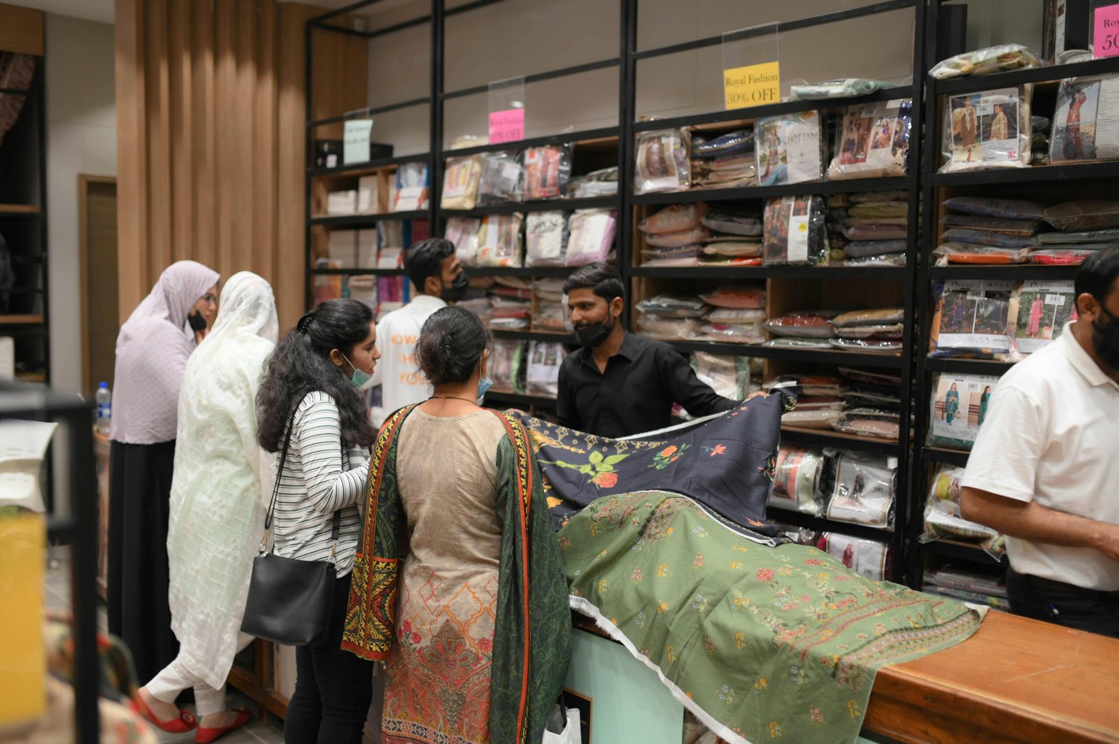 Customers exploring various handmade fabrics in a vibrant store setting.
